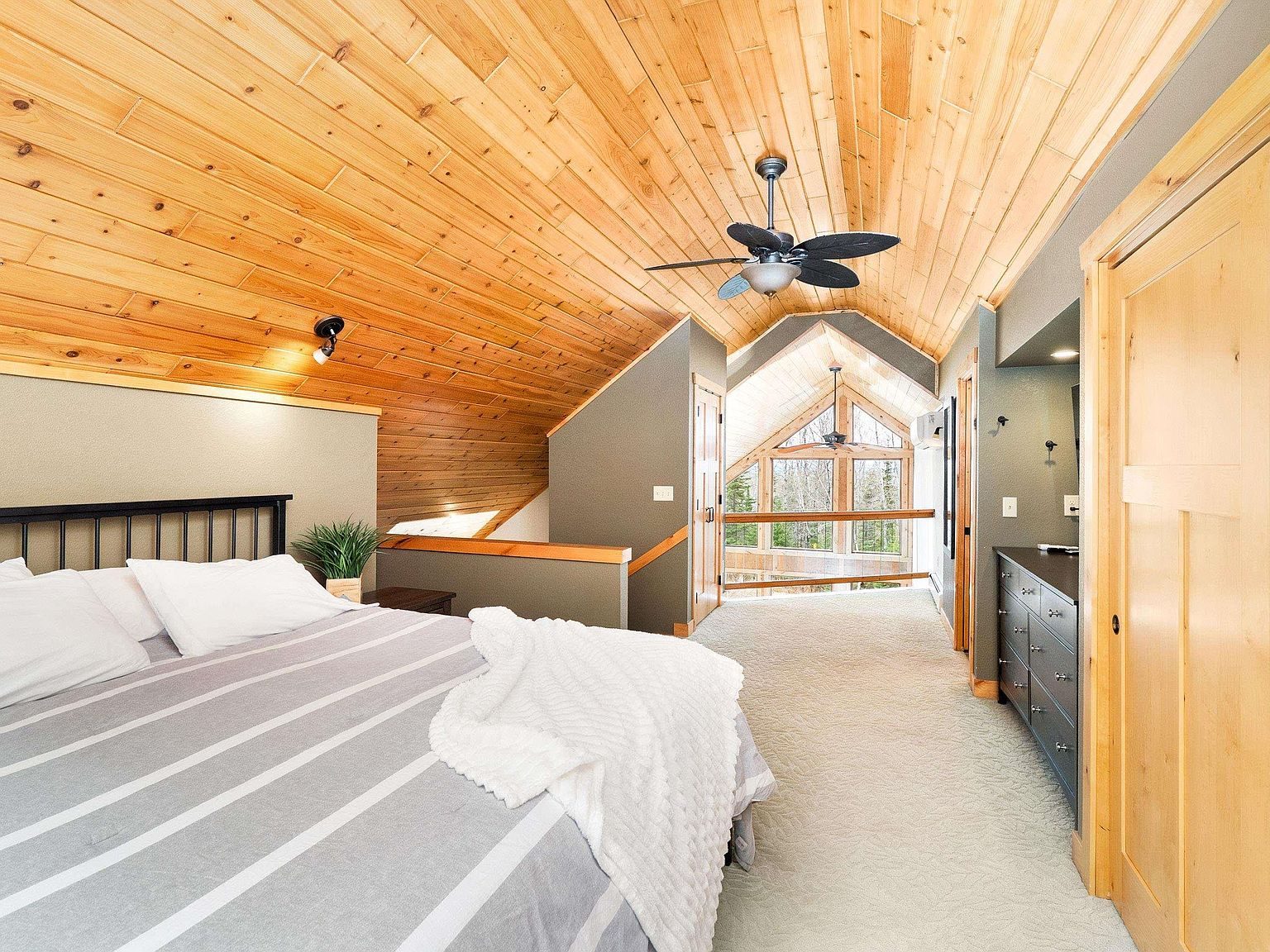 The primary bedroom under a vaulted pine ceiling